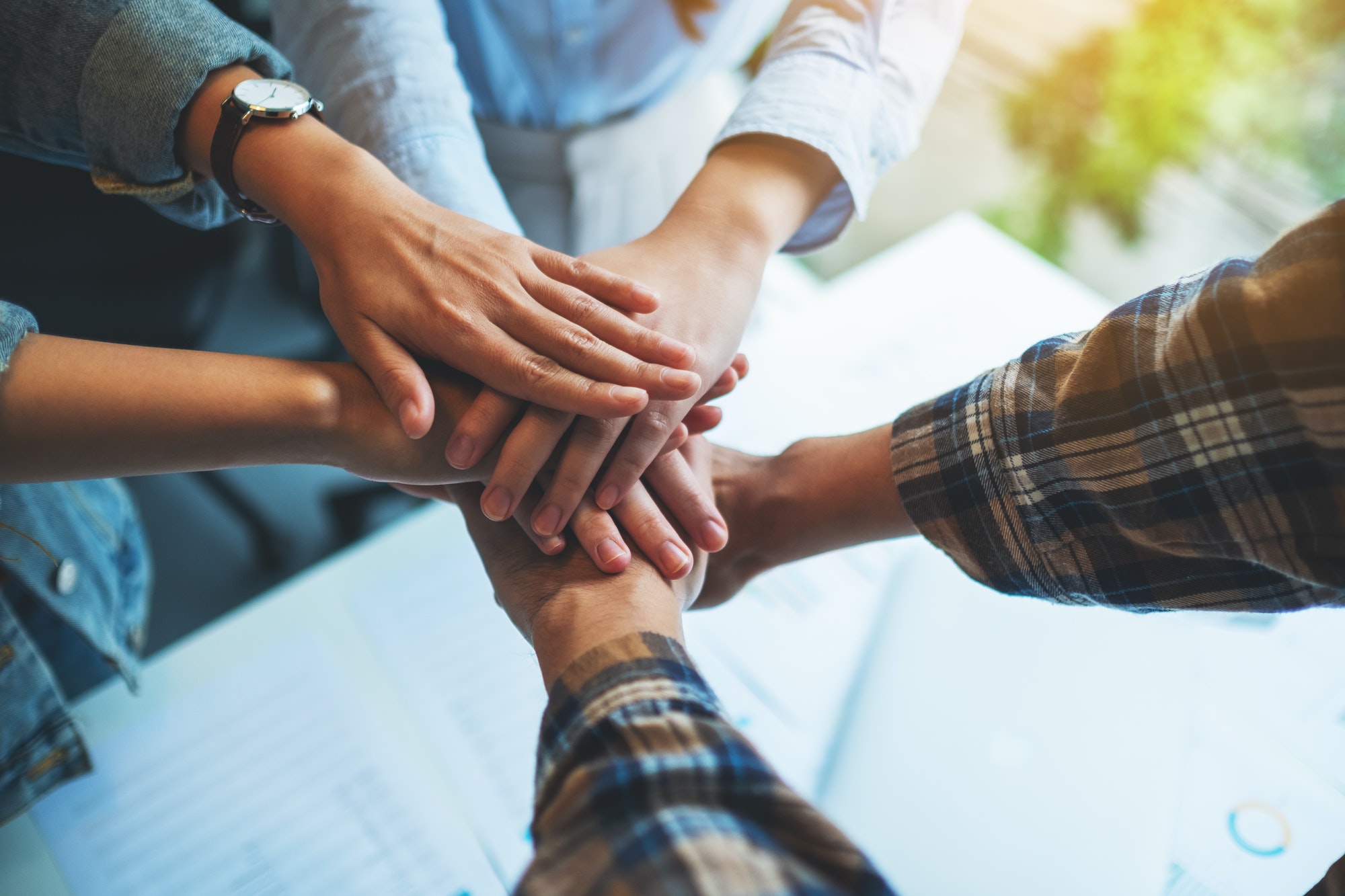 Closeup image of business team standing and joining their hands together in office